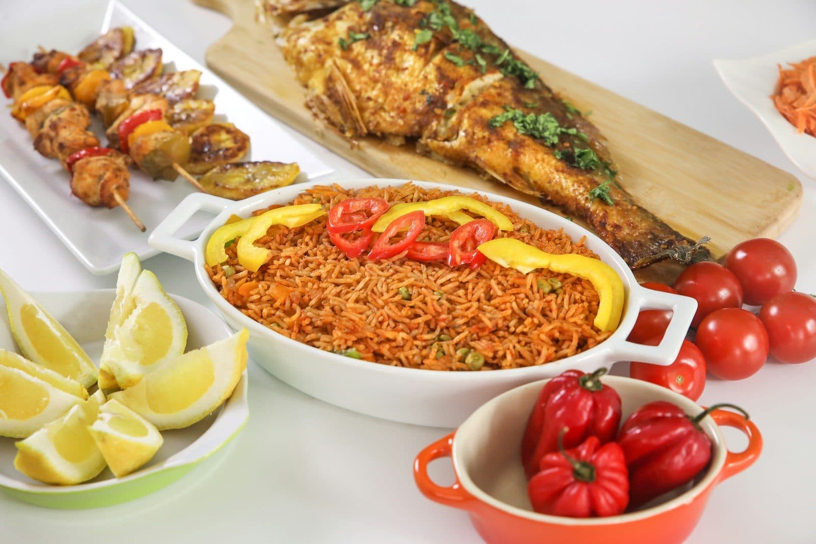 Jollof rice with grilled fish, skewers and fresh vegetables